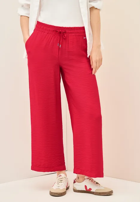 Rote, weite Hose mit Kordelzug und Taschen, dazu weiße Sneaker.